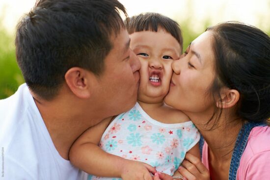 Parents Kissing their Small Child on the Cheek